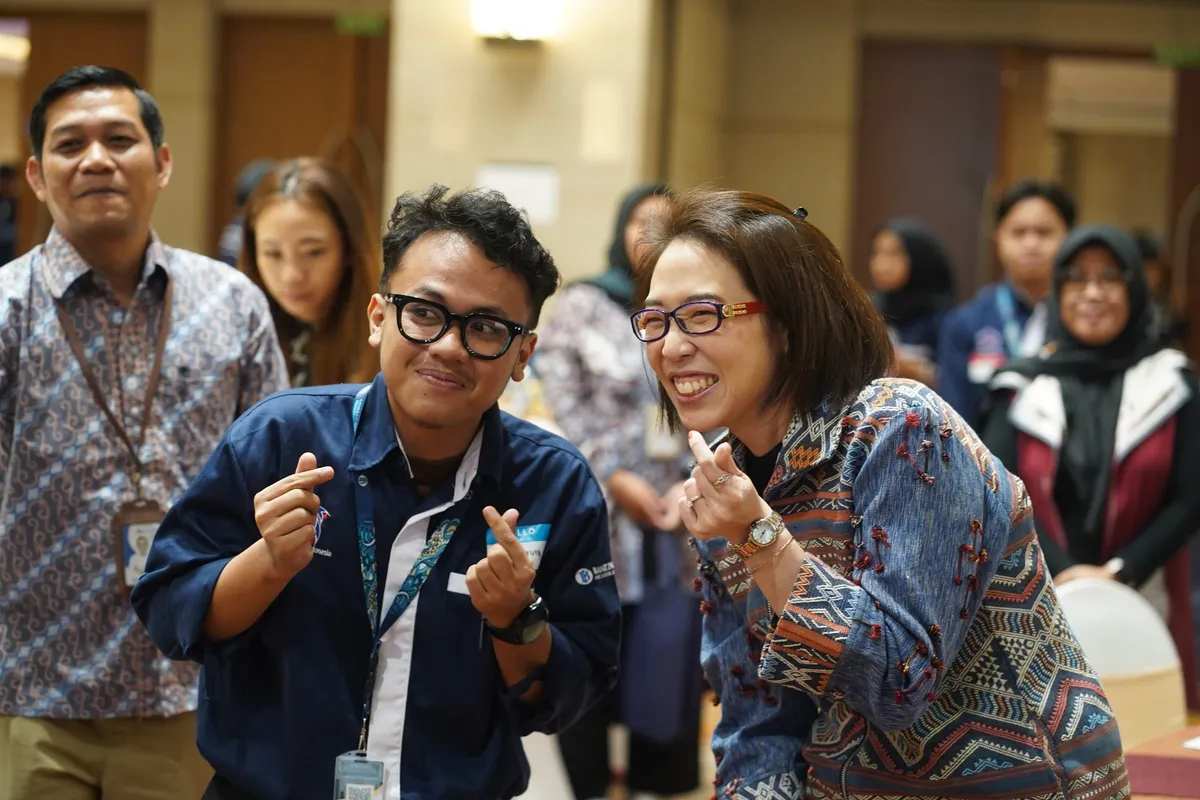 Dua peserta tersenyum dan membuat gestur hati dengan jari