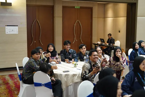 Peserta tertawa bersama di meja bundar selama sesi pelatihan
