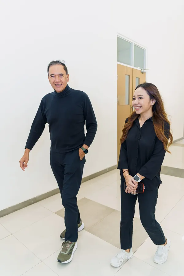Dua orang berjalan bersama di koridor sambil tersenyum